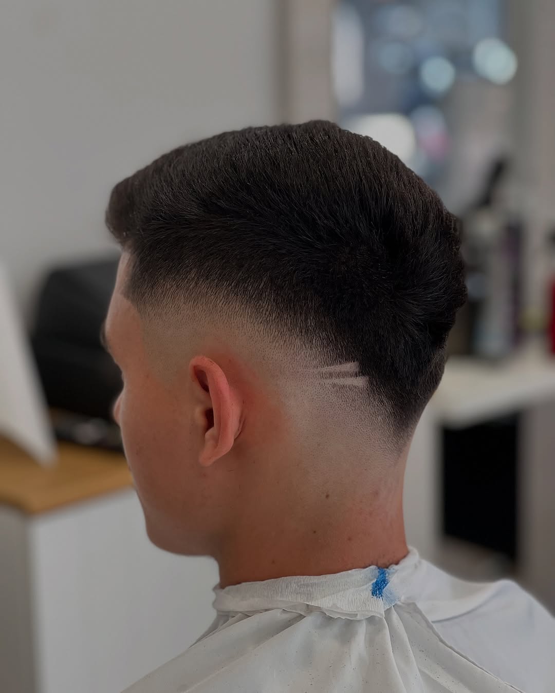Taper fade con dos líneas rasuradas sobre la oreja